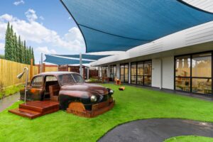 Nido Avondale Heights Terrace area with green grass, wooden car and transparent door
