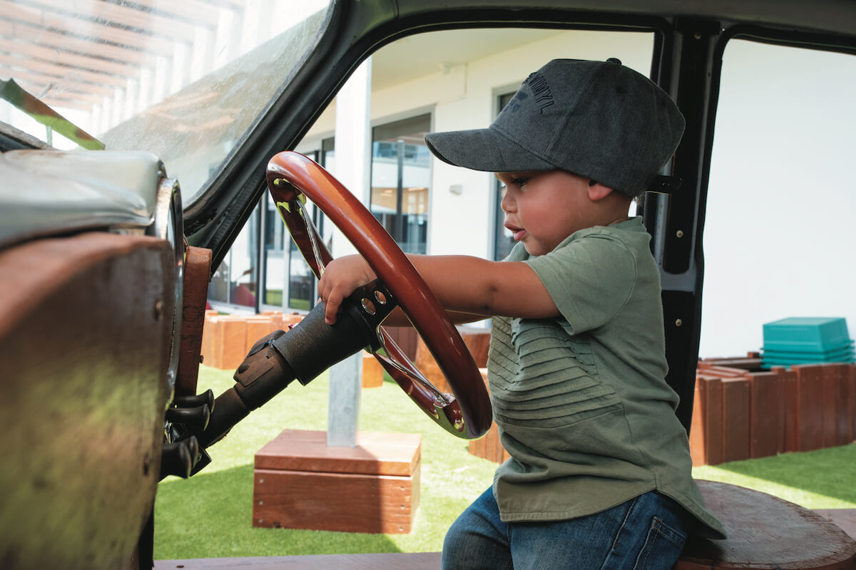 kid holding steering of a car at nido child care centre