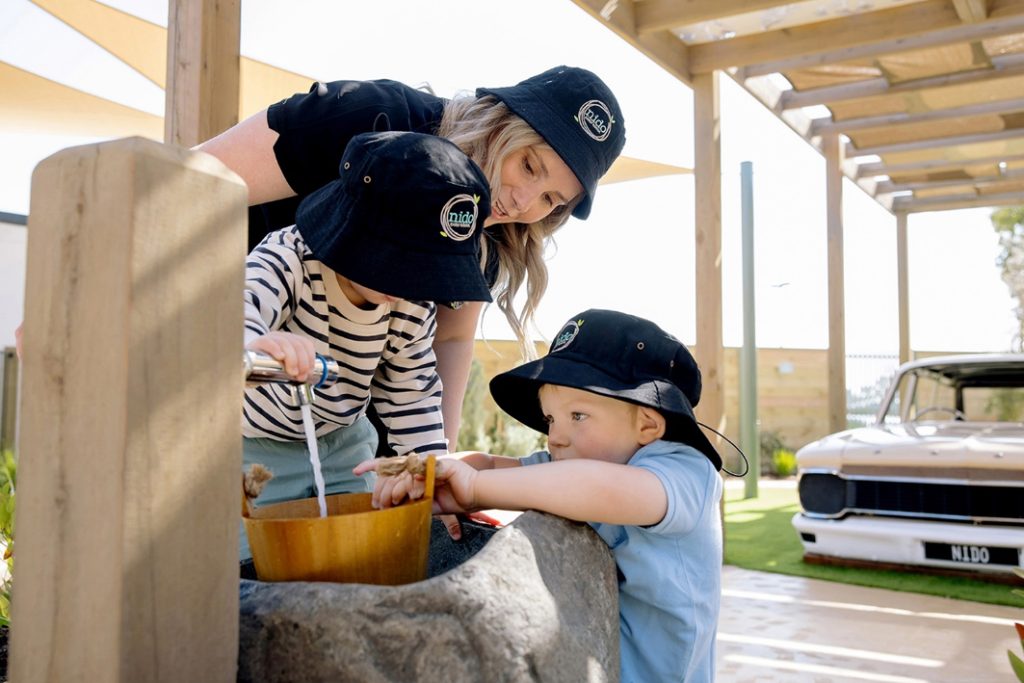 A Nido educator helps children in playing with water.