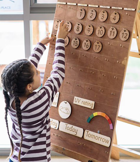 Girl child is learning to place numbers on number board